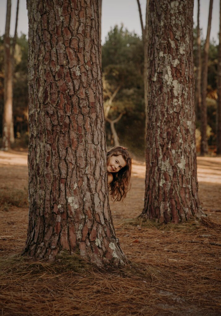 Séance photo petite fille cachée derriere un arbre qui sort la tête