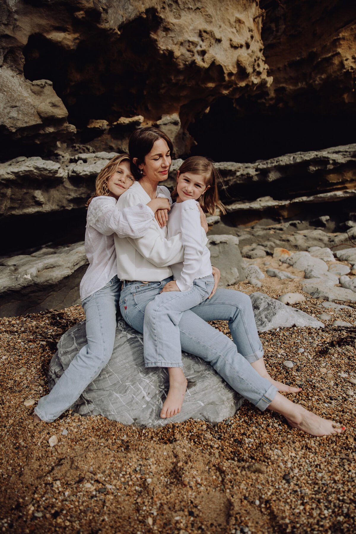 Portrait d'une maman et ses filles assistent sur un rocher enlacées
