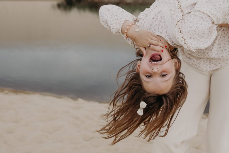 petite fille tête en l'air dans les bras de maman au courant d'huchet à Moliets